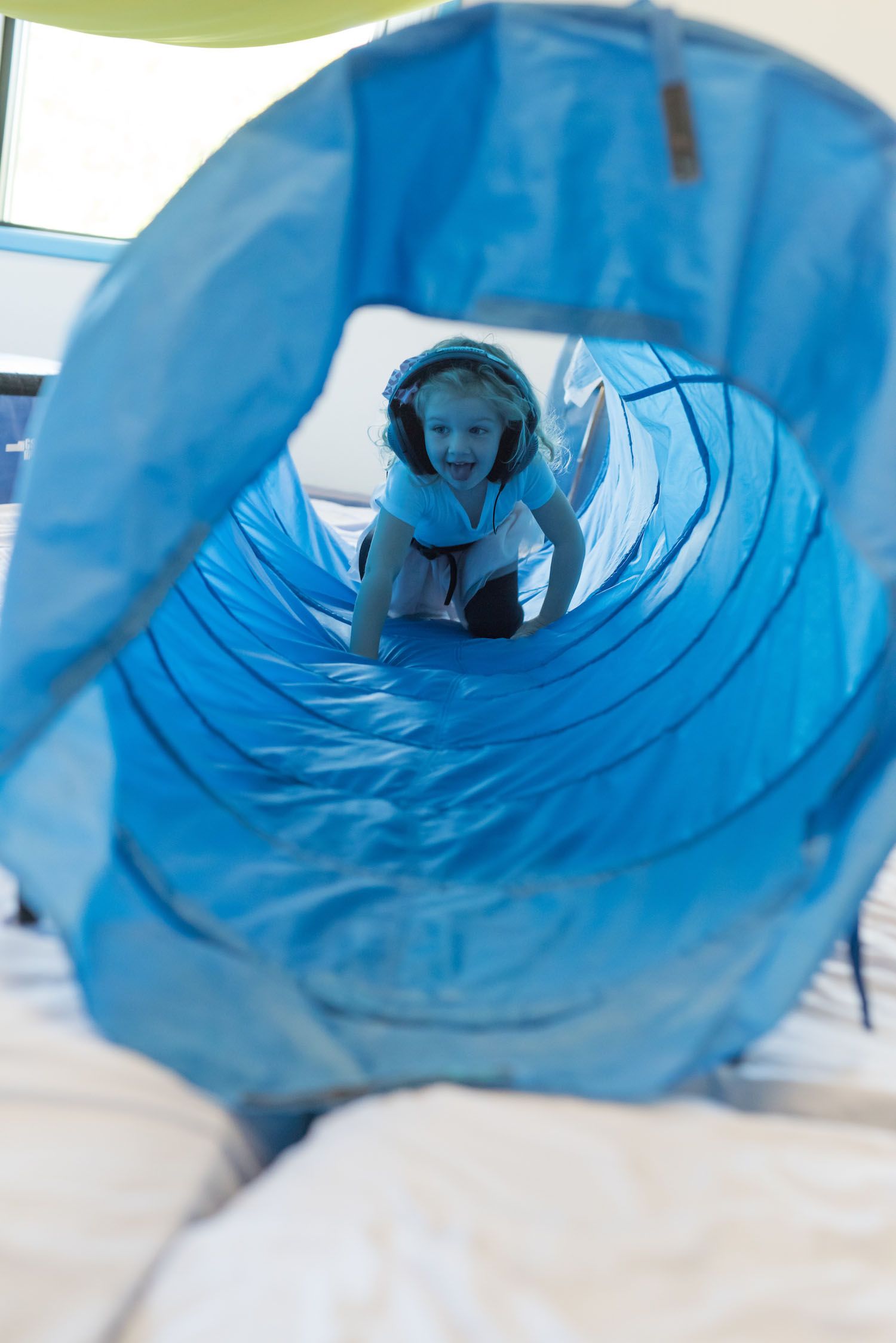 A child crawling through a toy tunnel representing therapeutic music programs offered by South Shore Therapies in Southern MA