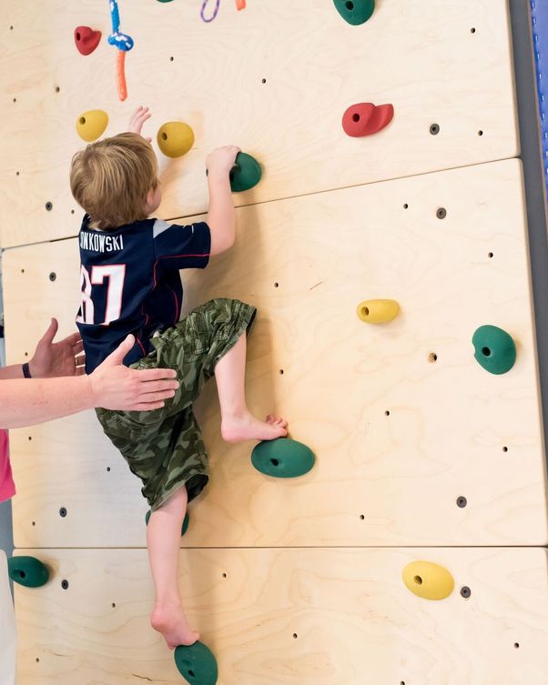 A child rock climbing representing pediatric occupational therapy done by speech and language therapy center South Shore Therapies in Southern MA 